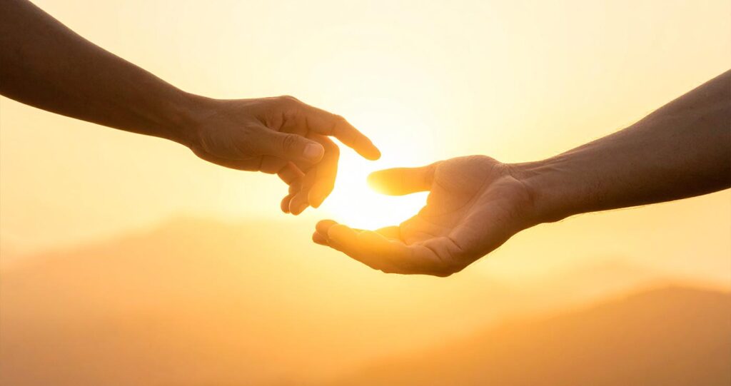 Two hands passing something small and glowing — like handing over a tool or a gift. Abstract, minimal, warm golden tones. The feeling of something created in private now being shared with the world.